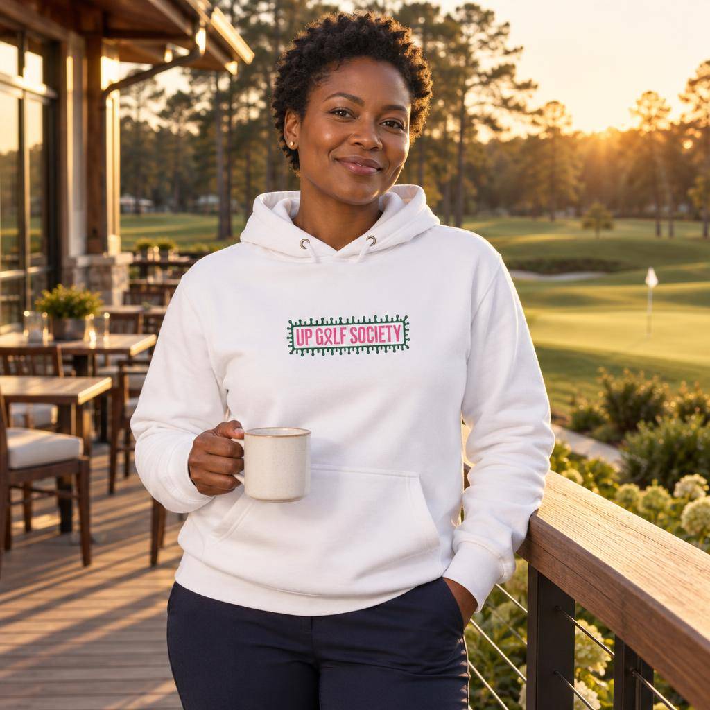 Hoodie blanc Octobre Rose Golf Ruban Rose UP Golf Society, porté de face sur la terrasse du club-house à l'heure dorée