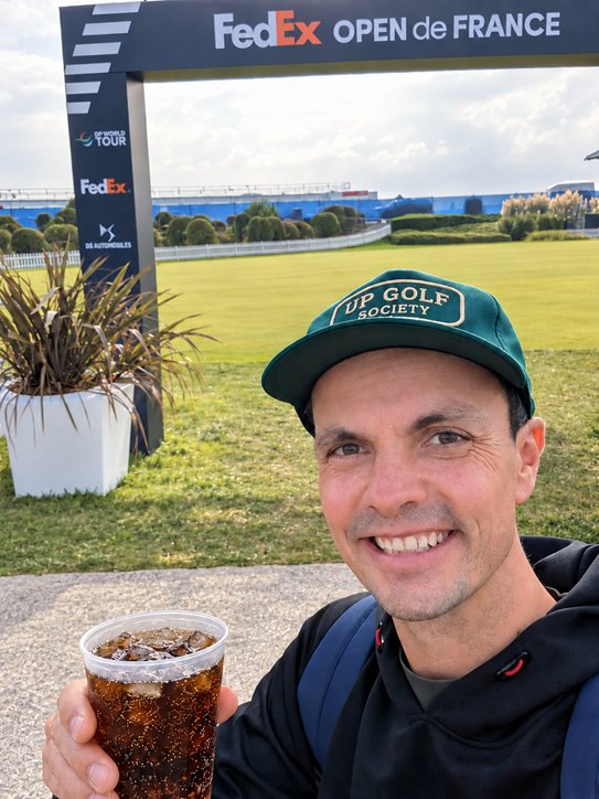 Grégoire Binet, fondateur de UP Golf Society, coiffé de la casquette UP Golf Society verte devant l’arche du FedEx Open de France